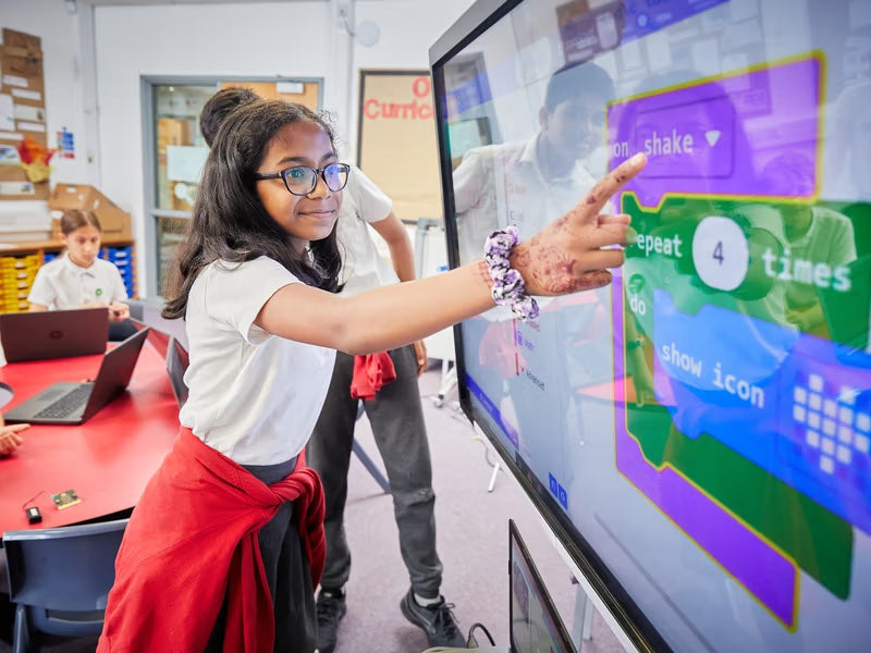 Female student pointing to block on Makecode