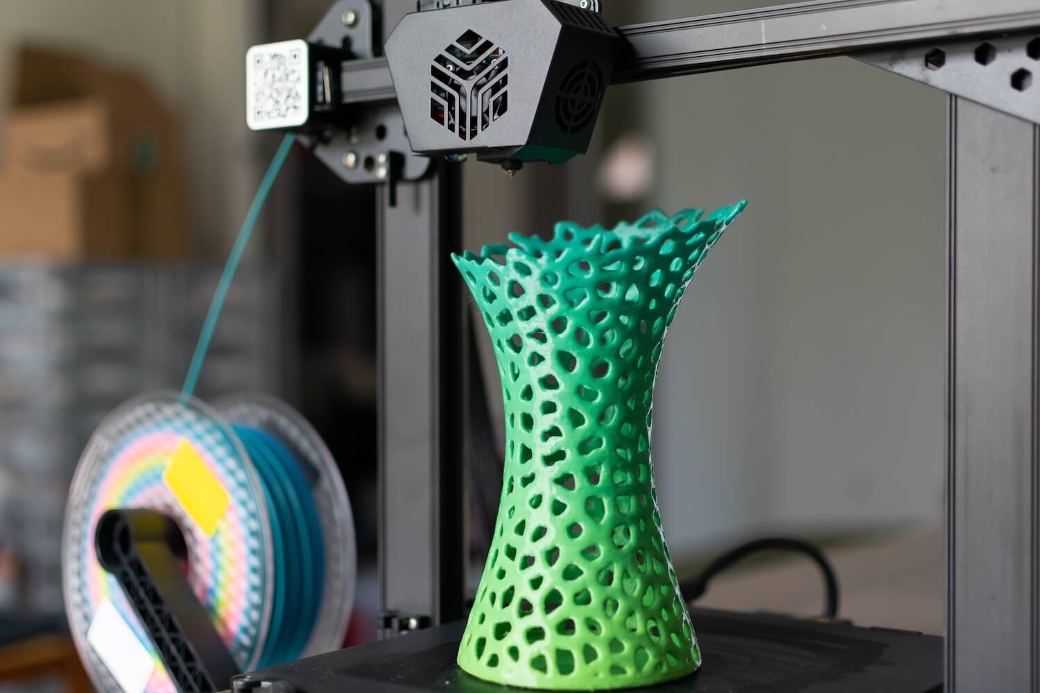 3D printer printing a multicoloured green and turquoise vase