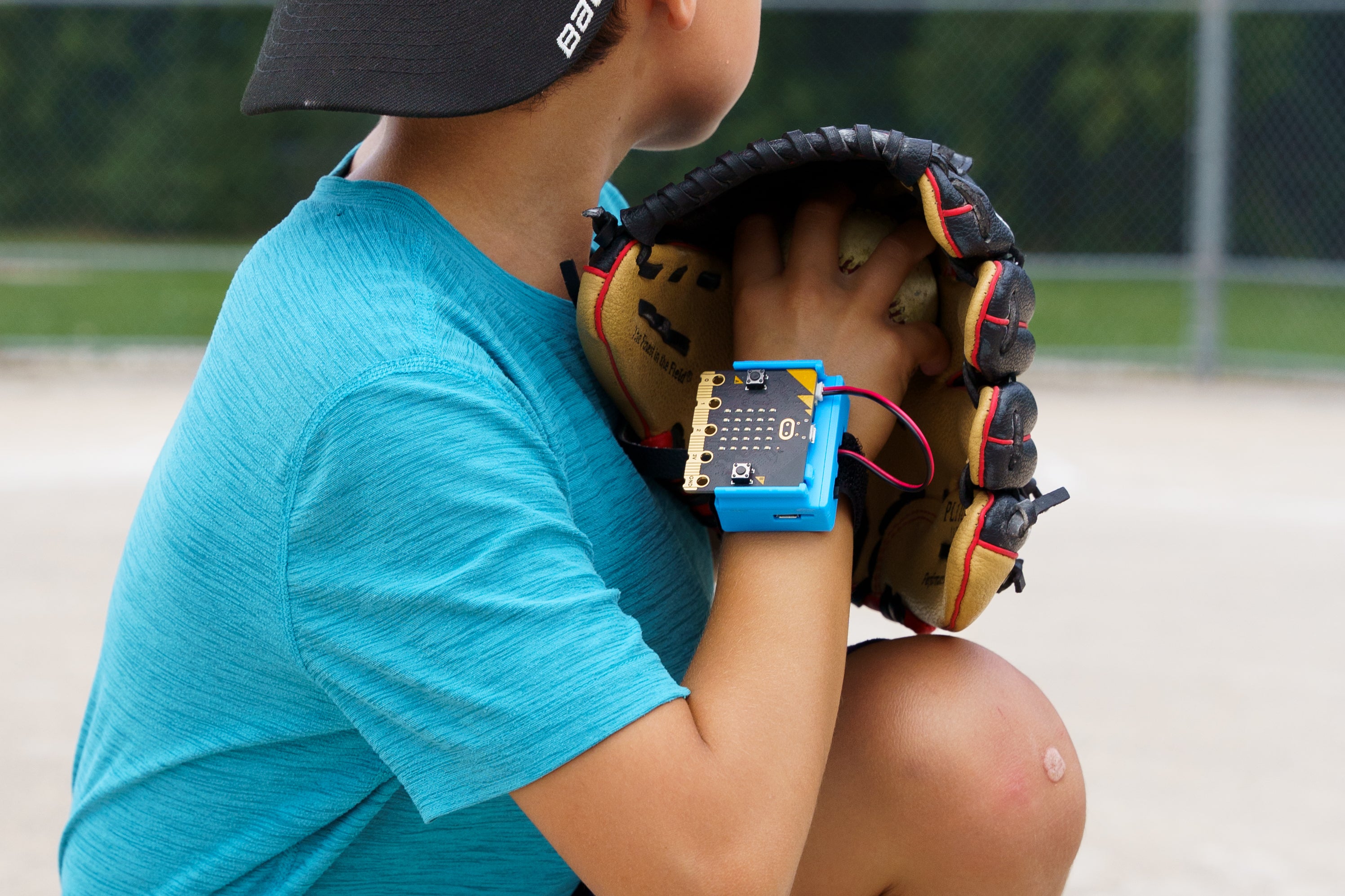 Male student throwing a baseball with CHARGE for micro:bit wrist strap