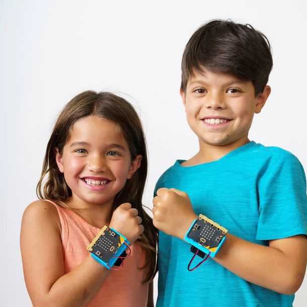 Two students smiling wearing CHARGE for micro:bit on their wrists