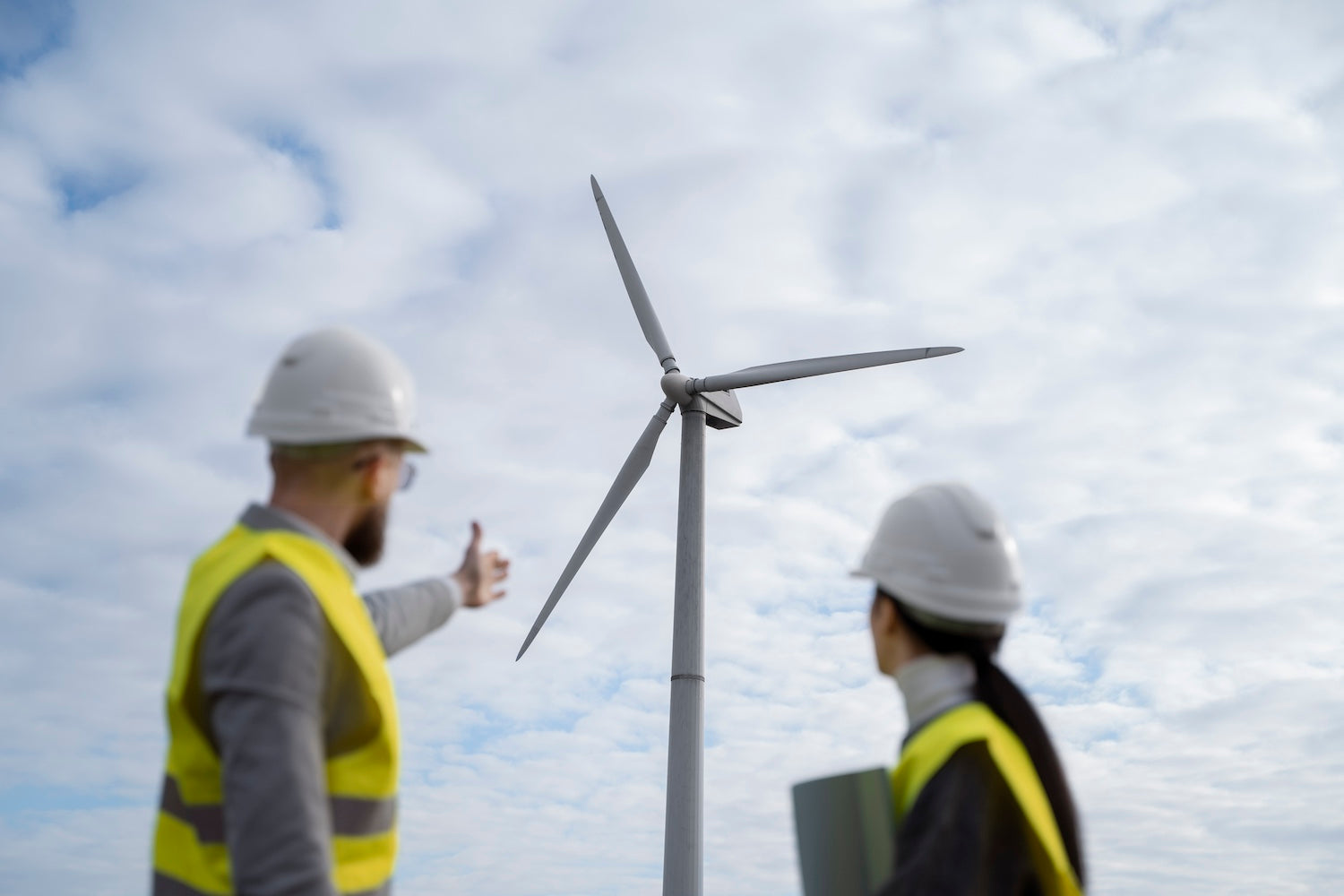 Two wind turbine technicians looking at a wind turbine